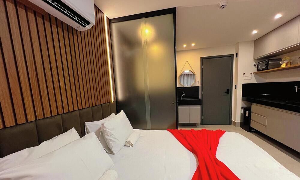 Une chambre d’hôtel moderne dotée d’un grand lit, d’un mur revêtu de panneaux en bois, d’une porte coulissante, d’un coin cuisine et d’un climatiseur fixé au plafond.