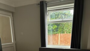 Un dormitorio con cama, escritorio y ventana con cortinas.