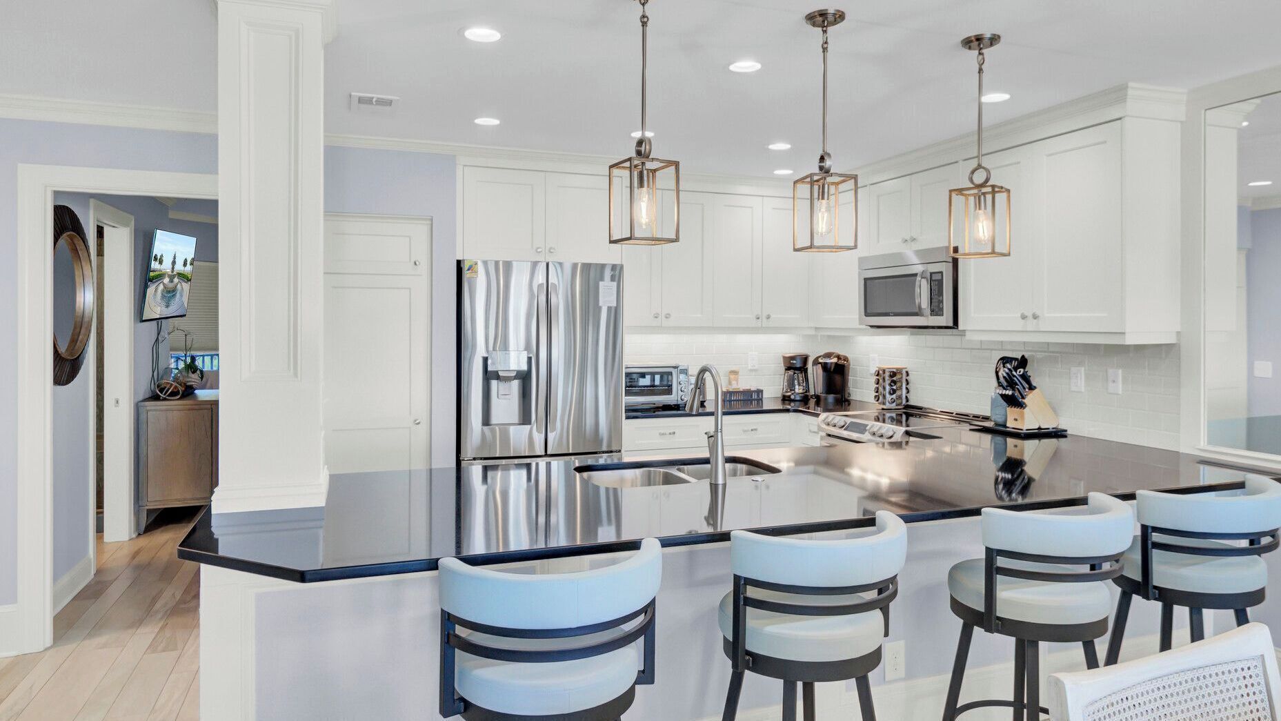 A modern kitchen with a central island, stainless steel appliances, and pendant lighting.