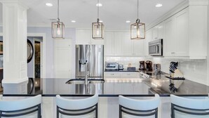 A modern kitchen with a central island, stainless steel appliances, and pendant lighting.