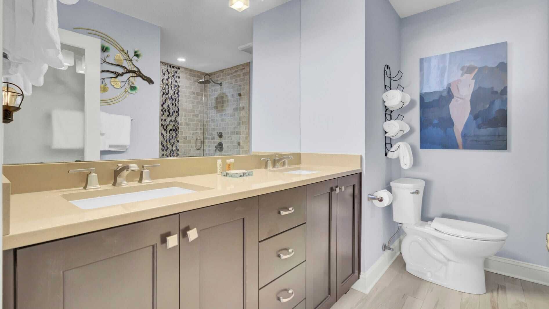 Une salle de bain moderne avec un meuble-lavabo à deux vasques, une douche avec une porte en verre et des toilettes.