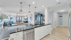 A modern kitchen with a central island, stainless steel appliances, and pendant lighting.