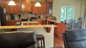 A modern kitchen with wooden cabinets, a granite countertop, and pendant lighting.