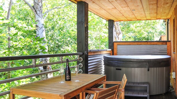 Eine Terrassenanlage aus Holz mit Whirlpool, Tisch und Stühlen.