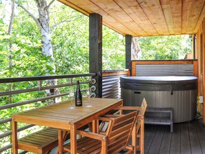 An outdoor wooden deck with a hot tub, a table, and chairs. - Peris Lodge - UK47606 (Caernarfon)
