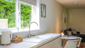 Eine moderne Küche mit weißer Arbeitsplatte, Spüle und Blick auf Grünflächen.