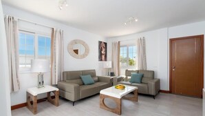 Ein modernes Wohnzimmer mit zwei Sofas, einem Couchtisch, einem Beistelltisch und einer Tür.