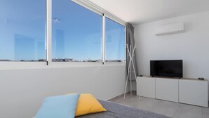 Ein modernes Zimmer mit großem Fenster, Flachbildfernseher und minimalistischem Design.