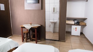 A hotel room with a bed, a small table with a chair, a TV mounted on the wall, a sink, and a refrigerator. - Hotel Portela III (Olímpia)