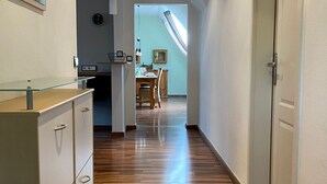 A hallway with wooden flooring, a kitchen area with a dining table, and a staircase leading to an upper level. - Ferienwohnung an der Schlösserachse . Ideal für Ausflüge ins Münsterland (Nordkirchen)