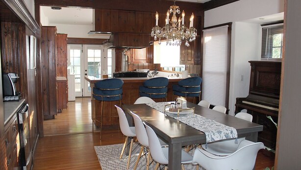 Un espace repas avec une longue table, des chaises blanches et un lustre.
