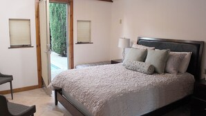Une chambre à coucher avec un lit, une table de chevet, une chaise et une fenêtre.