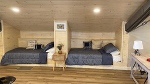 A room with two beds, wooden walls, a small table with a lamp, and a picture on the wall. - The Carriage House - Downtown (Chillicothe)