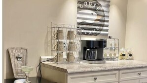 A kitchen with a coffee maker, a wine glass holder, and a decorative sign. - The Carriage House - Downtown (Chillicothe)