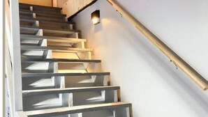 A staircase with a modern design, featuring a light-colored handrail and steps with geometric cutouts. - The Carriage House - Downtown (Chillicothe)