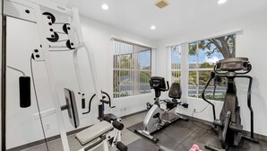A gym with exercise equipment, large windows, and a view of the outdoors.