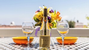 A bottle of wine, two glasses, and a yellow bowl on a table with a metal grid pattern. - Encantamar Escape by Avantstay Prime Location + Community Amenities (Laguna Niguel)