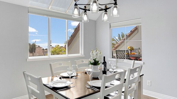 A dining area with a wooden table, white chairs, and a chandelier.