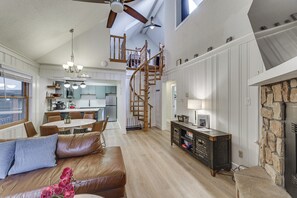 A spacious living area with a brown leather couch, a wooden staircase, and a stone fireplace. - Centrally Located Angel Fire Condo ~ 1/2 Mi Resort (Angel Fire)