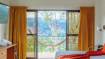Una habitación con cama, escritorio y ventana con cortinas.