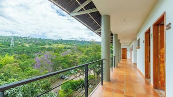 Un pasillo con vistas a un paisaje exuberante, piso de baldosas y un balcón con barandilla.