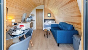 A compact, wooden interior with a dining area, kitchenette, and a sleeping area with a blue sofa. - 1 bedroom accommodation in Talybont, near Borth (Talybont, near Borth)