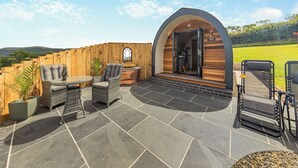 An outdoor patio with wicker furniture, a stone floor, and a wooden fence. - 1 bedroom accommodation in Talybont, near Borth (Talybont, near Borth)
