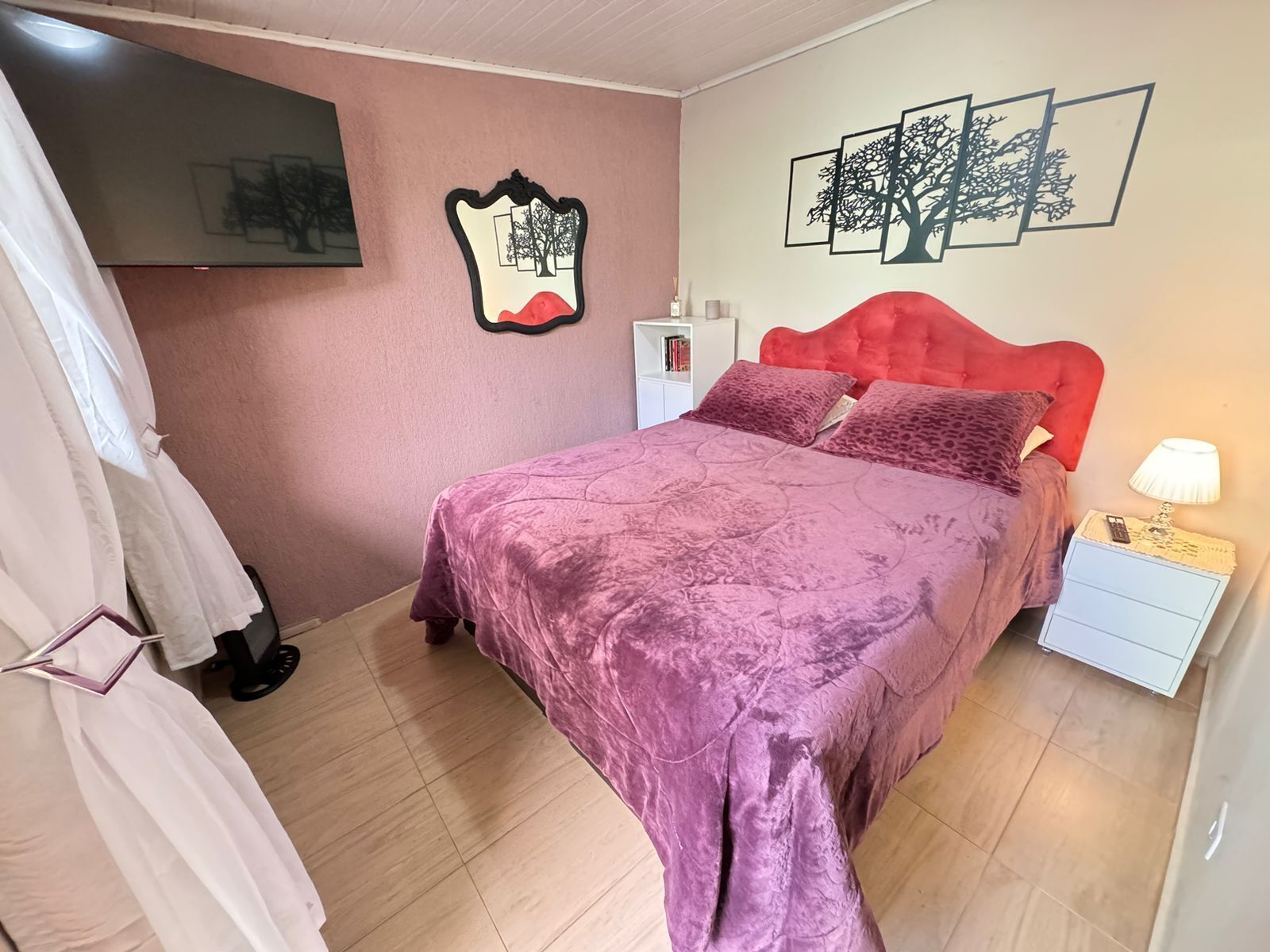 A bedroom with a bed, a nightstand, a lamp, a wardrobe, and wall art.