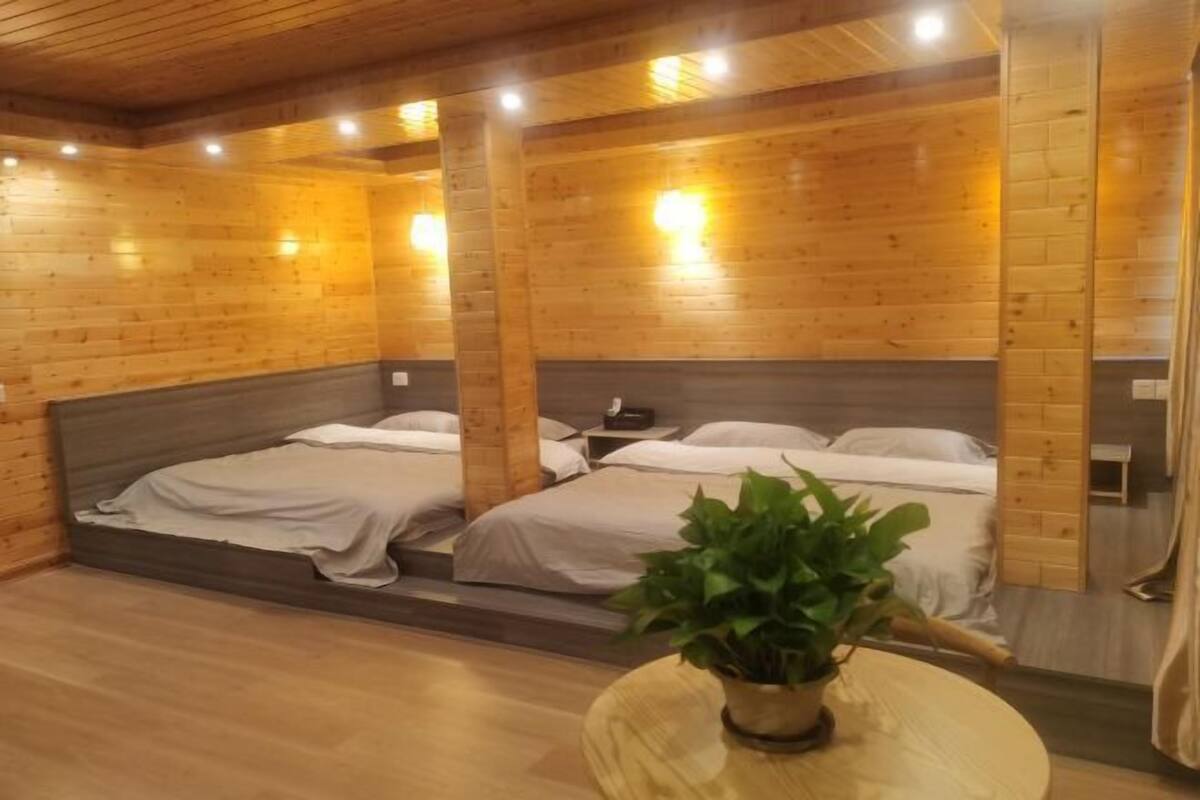 A wooden cabin-style room with two beds, a small table with a plant, and a wooden cabinet.