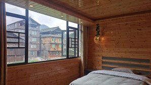 A wooden-paneled room with a large window, a bed, and a wall-mounted light fixture. - Sanjiang Qingtian Yuese Homestay (Sanjiang)
