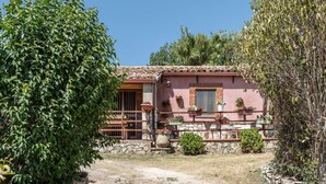 Una casa rustica con fondamenta in pietra, tetto in tegole e un portico in legno con piante in vaso.