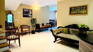 A spacious living area with a sofa, chairs, a dining table, and a staircase. - Rivorich Residence Kandy (Sirimalwatta)