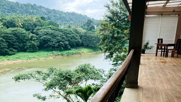A balcony with a view of a river and dense greenery. - Rivorich Residence Kandy (Sirimalwatta)