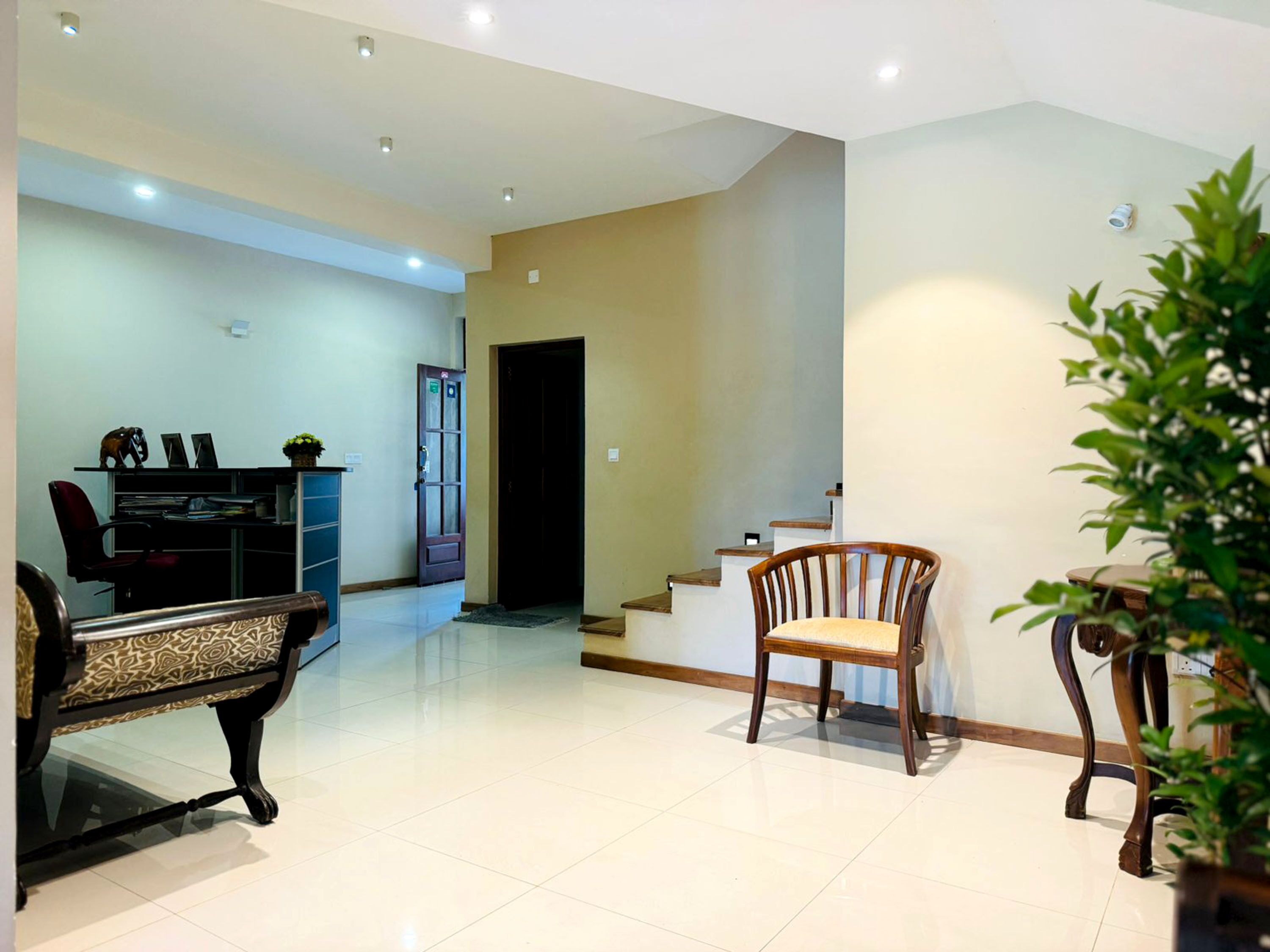 A spacious living area with a sofa, a wooden chair, and a dining table.