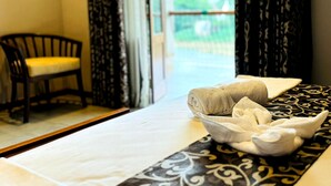 A hotel room with a bed, a chair, and a view of a green landscape through the window. - Rivorich Residence Kandy (Sirimalwatta)
