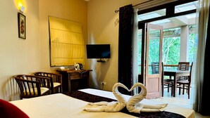 A hotel room with a bed, a desk, a chair, a TV, and a balcony with a table and chairs. - Rivorich Residence Kandy (Sirimalwatta)