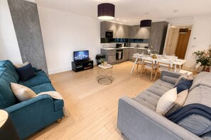 A modern living room with a sofa, a coffee table, and a television.