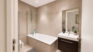 A modern bathroom with a bathtub, shower, and vanity.