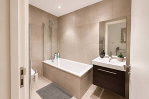 A modern bathroom with a bathtub, shower, and vanity.