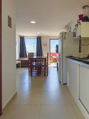 A kitchen with a refrigerator, microwave, and a blender on the counter. - Encanto Vermelho Búzios (Búzios)