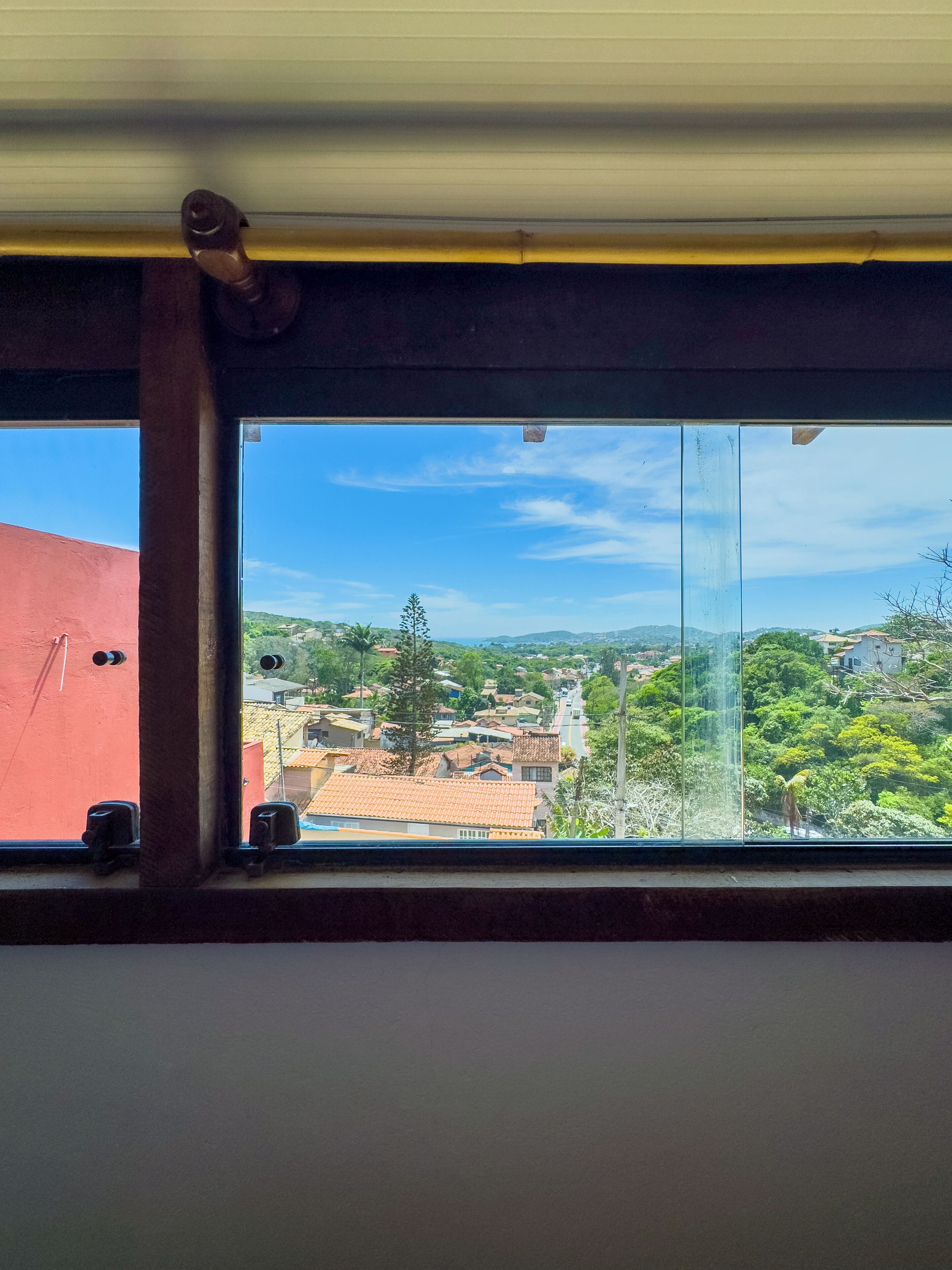 Une fenêtre offrant une vue dégagée sur un quartier résidentiel, avec des maisons et de la verdure.