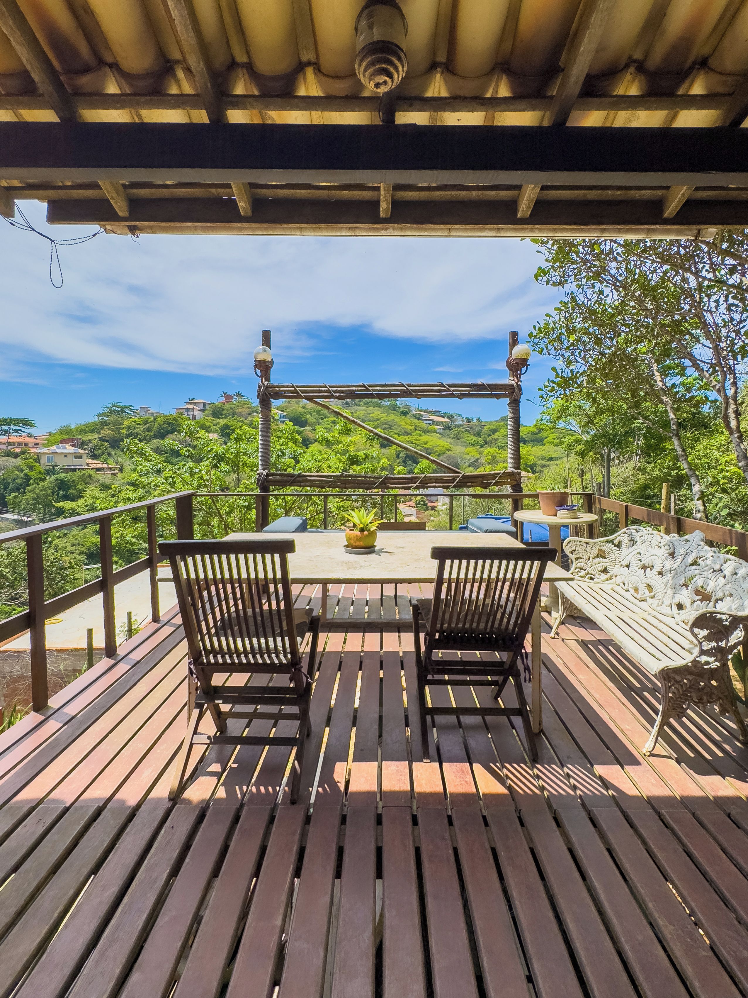 Una terraza de madera con una mesa y sillas, con vistas a un paisaje verde exuberante.