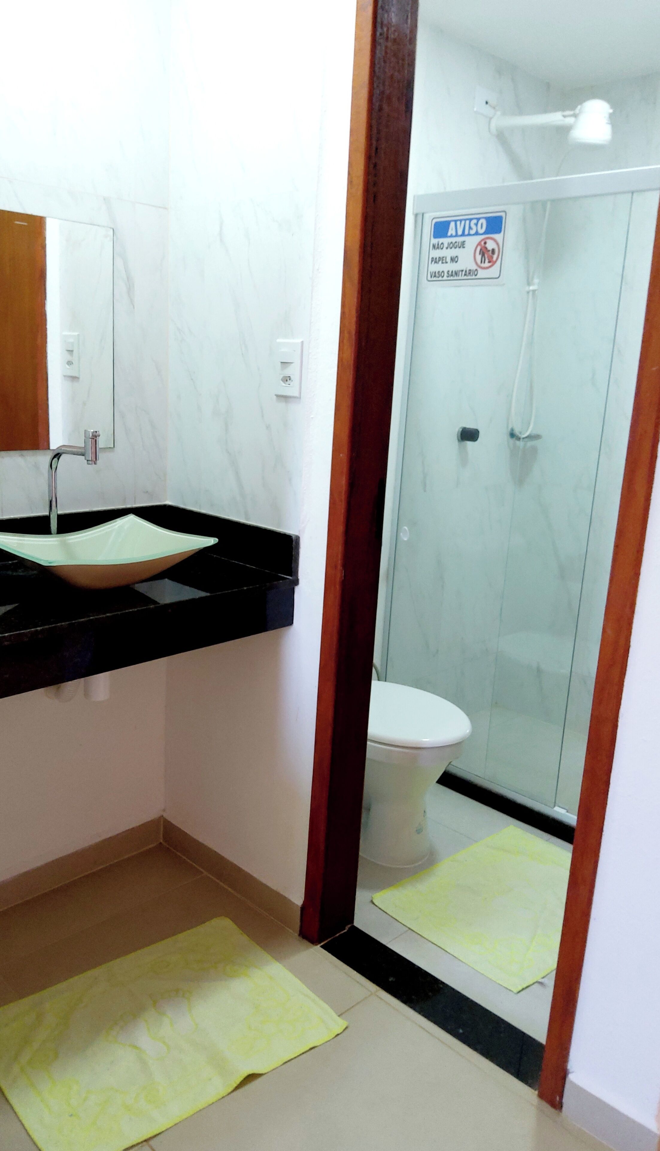 A bathroom with a black sink, a mirror, a toilet, and a shower.