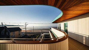 A balcony with a curved wooden ceiling overlooking a beach. - The Nevada (York Beach)
