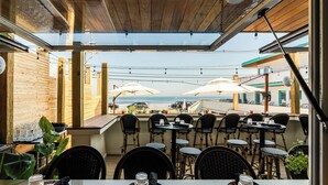 An outdoor dining area with tables and chairs, overlooking a beach. - The Nevada (York Beach)