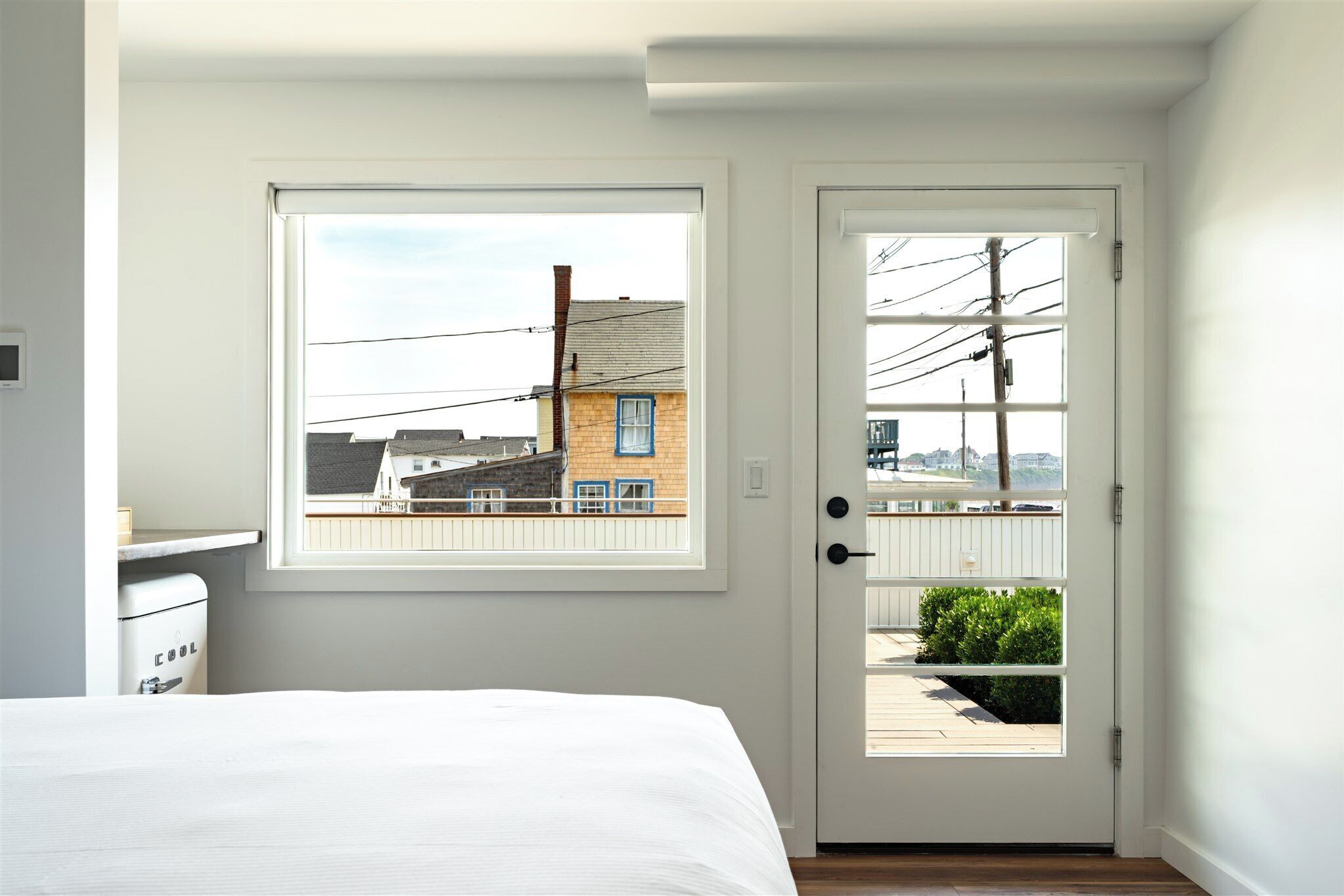 A bedroom with a bed, a window, and a door leading to a balcony.
