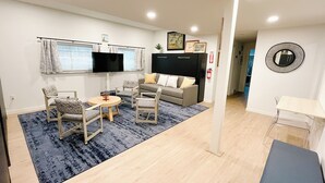 A modern living room with a sofa, chairs, a TV, and a small table.