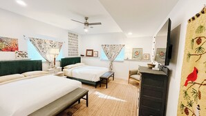 A bedroom with two beds, a desk, a chair, a mirror, and a ceiling fan.