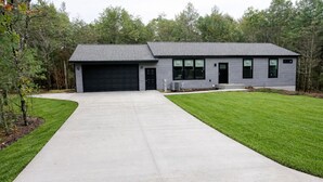 A modern two-story house with a grey exterior, a black garage door, and a well-maintained lawn.