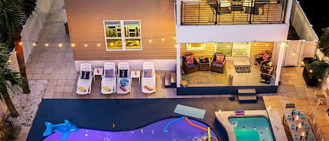 Una casa de dos pisos con piscina, sillas de descanso y jacuzzi.